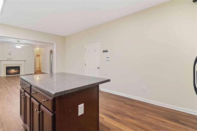 kitchen featuring ceiling fan, hardwood / wood-style flooring, dark brown cabinets, and a kitchen island