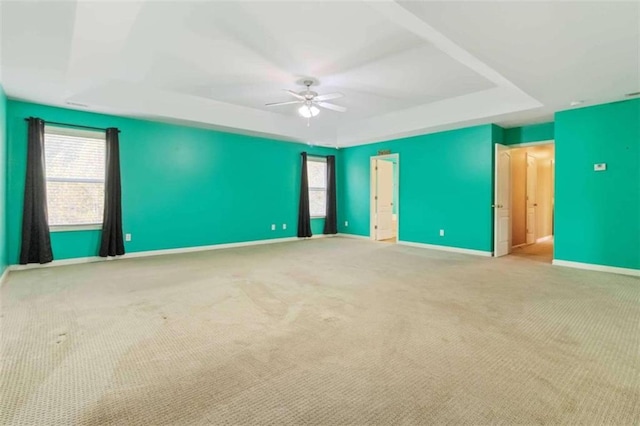 interior space featuring light colored carpet, ceiling fan, and a raised ceiling