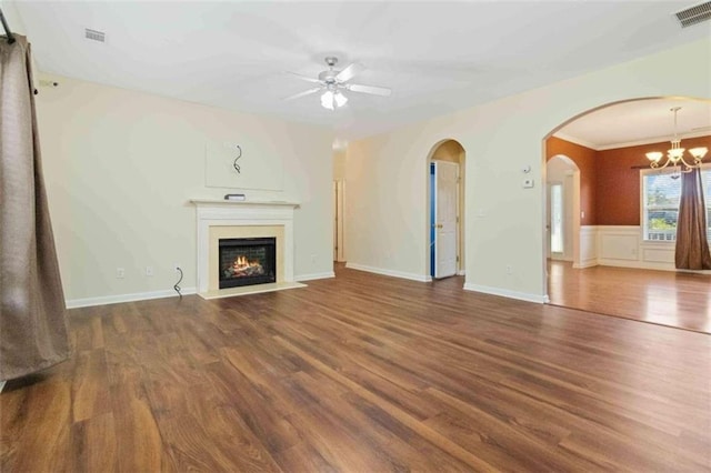 unfurnished living room with dark wood-type flooring, ceiling fan with notable chandelier, and crown molding