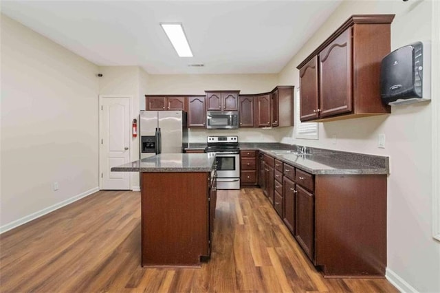 kitchen with dark hardwood / wood-style flooring, a center island, dark brown cabinetry, sink, and appliances with stainless steel finishes