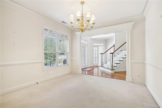 empty room featuring an inviting chandelier, crown molding, decorative columns, and carpet