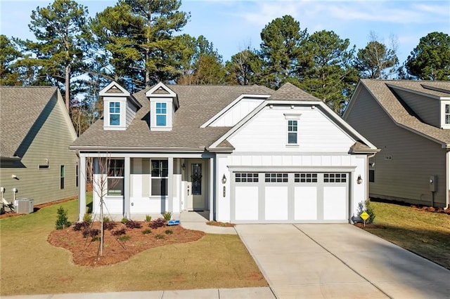 view of front facade with a front lawn, central air condition unit, covered porch, and a garage