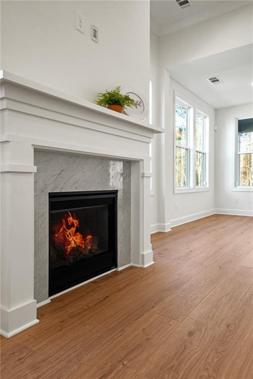 unfurnished living room with wood-type flooring, crown molding, and a premium fireplace