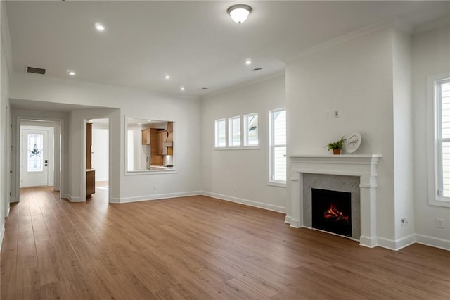 unfurnished living room with wood-type flooring, crown molding, a fireplace, and plenty of natural light