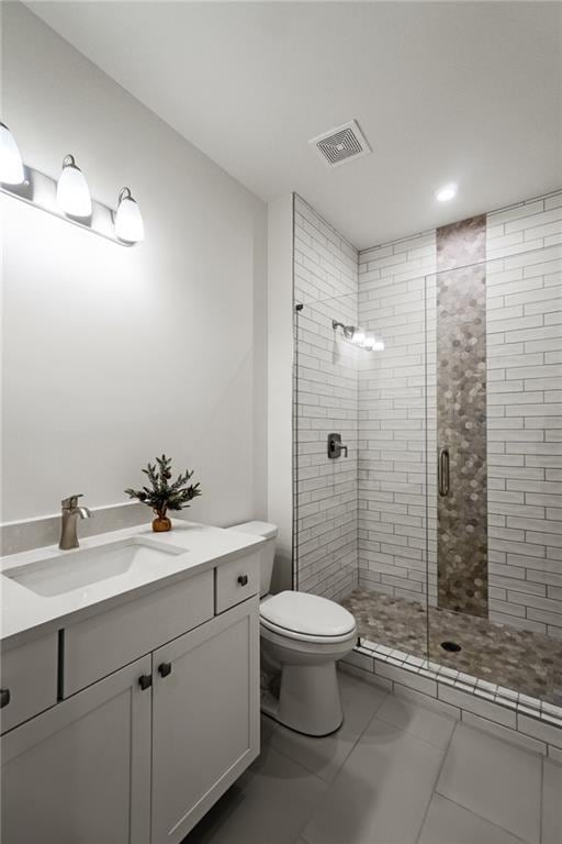 bathroom featuring walk in shower, vanity, tile patterned floors, and toilet