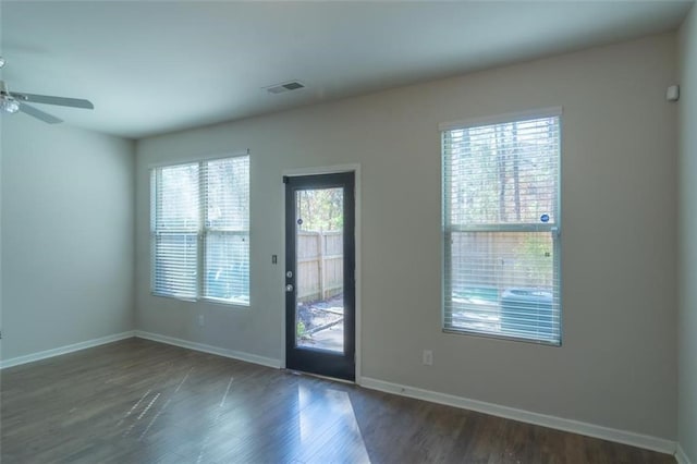 doorway featuring dark wood-style flooring, visible vents, ceiling fan, and baseboards