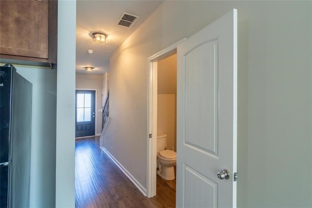 hallway with dark wood-style floors, visible vents, and baseboards