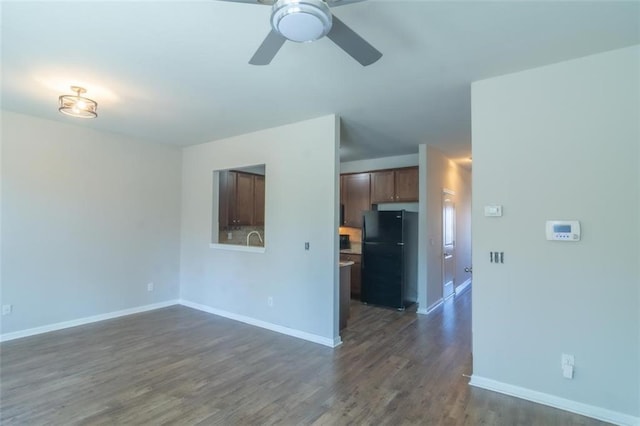 unfurnished living room featuring dark wood-type flooring, a ceiling fan, and baseboards