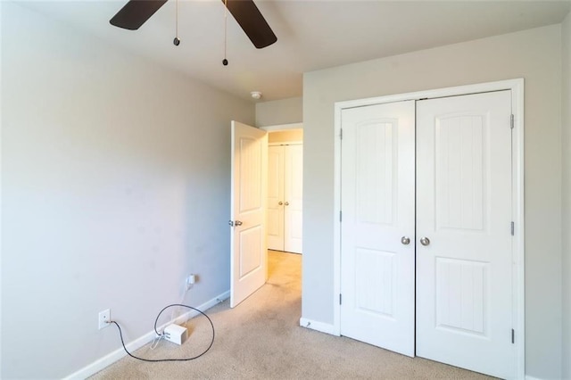 unfurnished bedroom with ceiling fan, baseboards, a closet, and light colored carpet