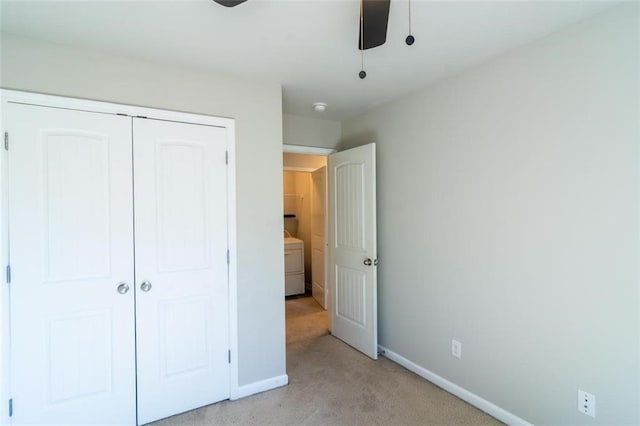 unfurnished bedroom featuring baseboards, washer / clothes dryer, a closet, and light colored carpet