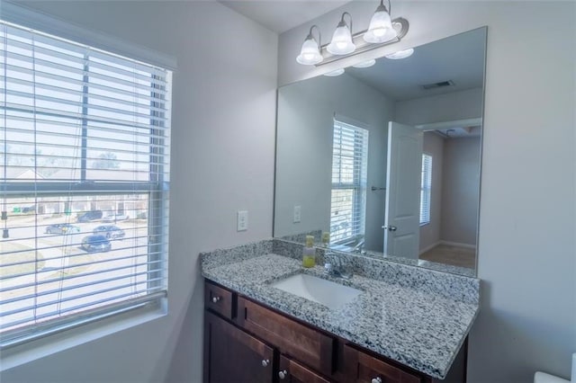 bathroom with toilet, vanity, and visible vents