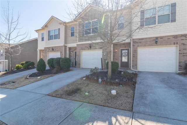 view of property with an attached garage, concrete driveway, and brick siding