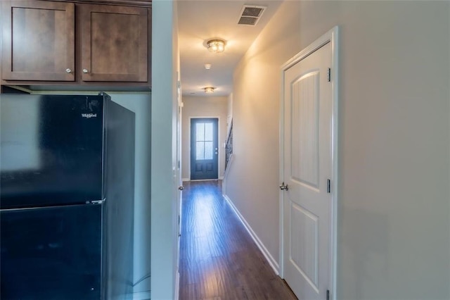 hall with dark wood-style flooring, visible vents, and baseboards