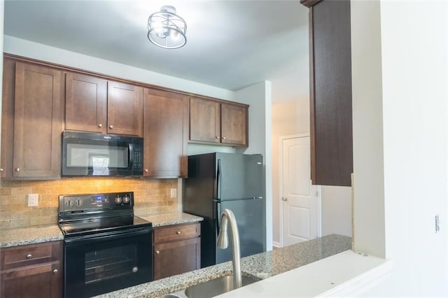 kitchen with light stone countertops, black appliances, dark brown cabinets, and backsplash