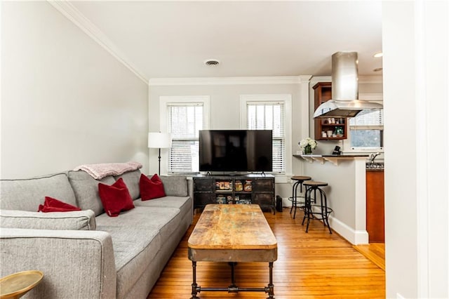 living area with crown molding, light wood-style floors, and baseboards