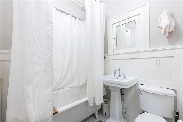 full bath with toilet, shower / bathtub combination with curtain, and a decorative wall