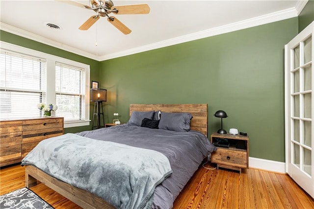bedroom featuring wood finished floors, crown molding, baseboards, and ceiling fan