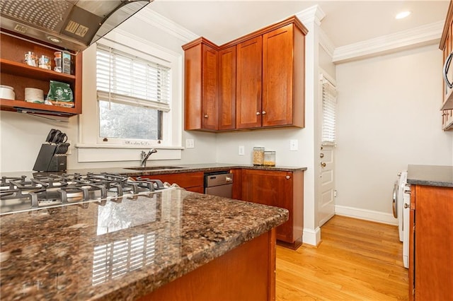 kitchen with crown molding, a sink, light wood finished floors, baseboards, and dark stone countertops