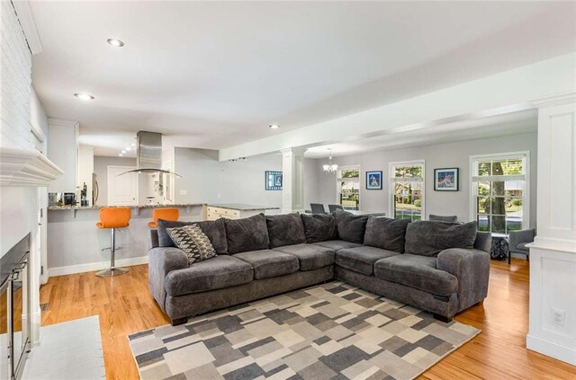 living room featuring decorative columns, light hardwood / wood-style flooring, and a notable chandelier