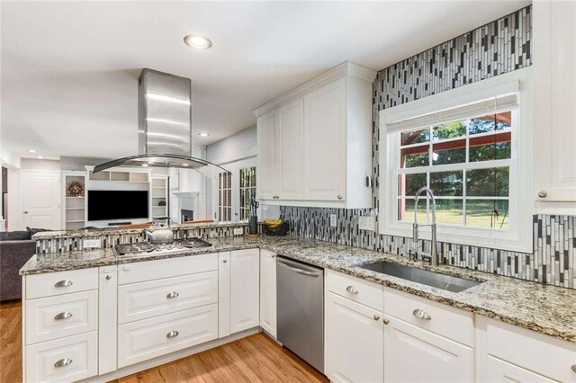 kitchen with appliances with stainless steel finishes, sink, kitchen peninsula, white cabinetry, and light hardwood / wood-style floors