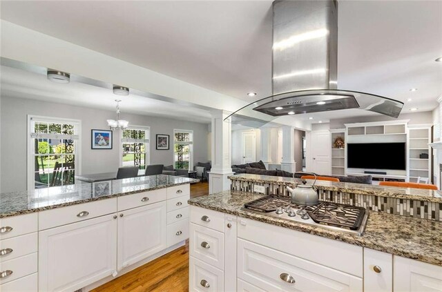 kitchen with ornate columns, light stone counters, plenty of natural light, and stainless steel gas cooktop