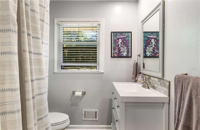 bathroom featuring vanity, toilet, and tasteful backsplash