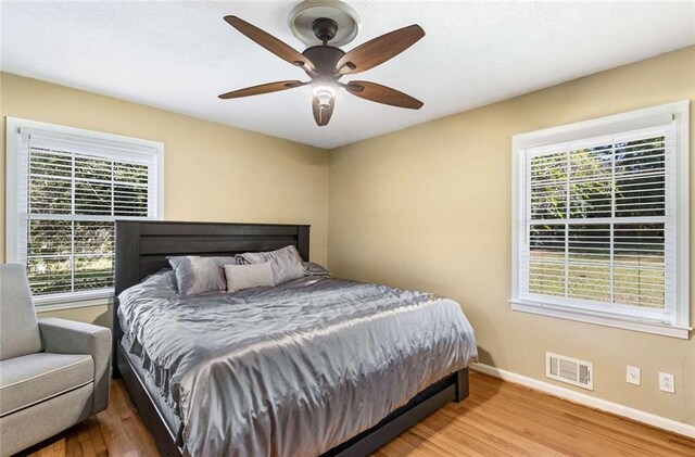 bedroom featuring multiple windows, hardwood / wood-style flooring, and ceiling fan