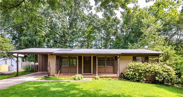 ranch-style home with a front yard, a carport, and a porch