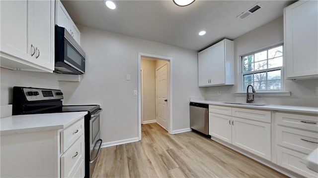 kitchen featuring white cabinetry, stainless steel appliances, sink, and light wood-type flooring