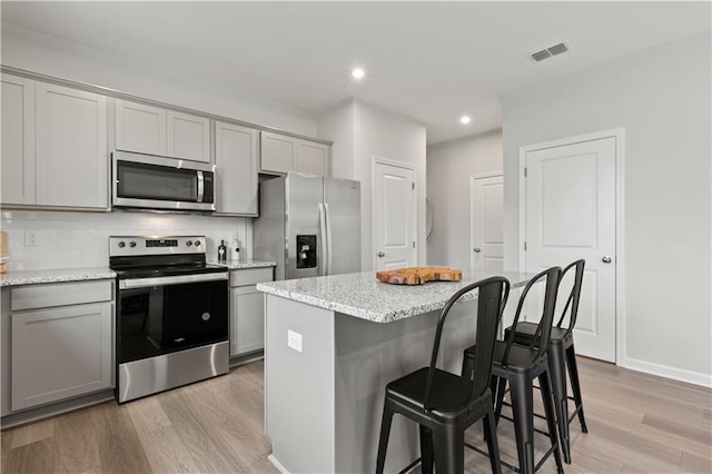 kitchen with gray cabinetry, a kitchen island, and appliances with stainless steel finishes