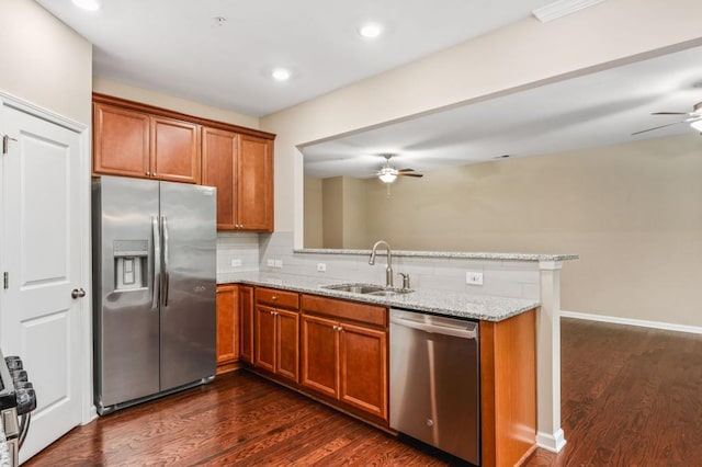 kitchen featuring dark hardwood / wood-style floors, light stone countertops, stainless steel appliances, and kitchen peninsula