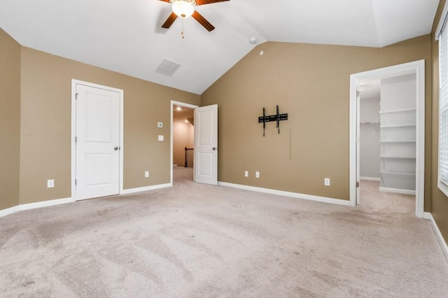 unfurnished bedroom featuring a spacious closet, ceiling fan, light colored carpet, and lofted ceiling