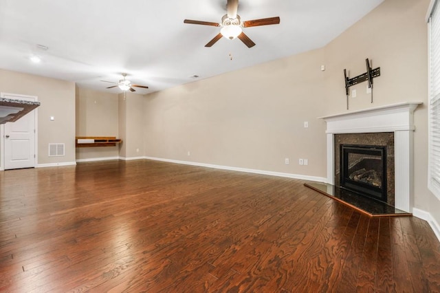 unfurnished living room featuring a premium fireplace, ceiling fan, and dark wood-type flooring