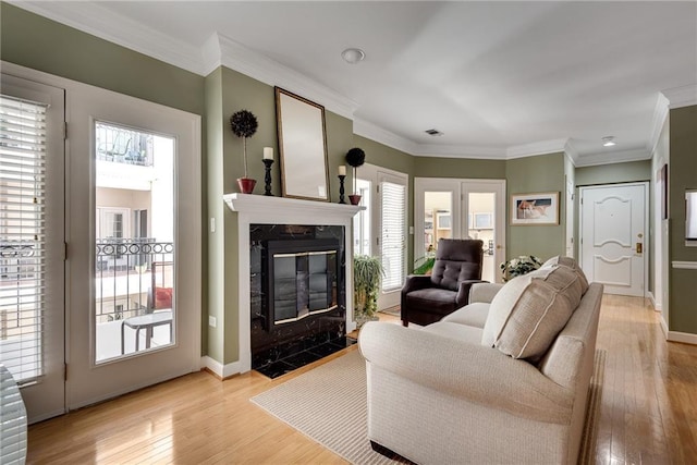 living room featuring visible vents, ornamental molding, baseboards, light wood-type flooring, and a high end fireplace