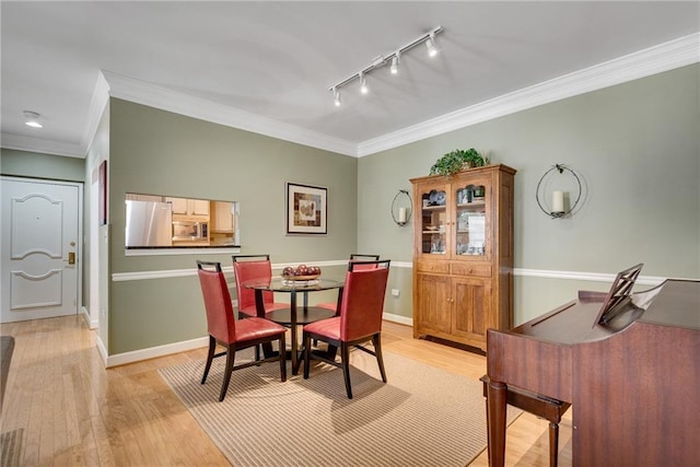 dining room with rail lighting, light wood finished floors, and ornamental molding