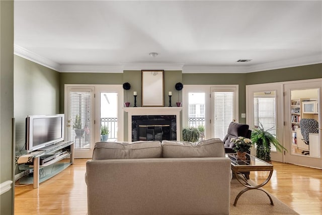 living room featuring visible vents, light wood-type flooring, a wealth of natural light, and a high end fireplace