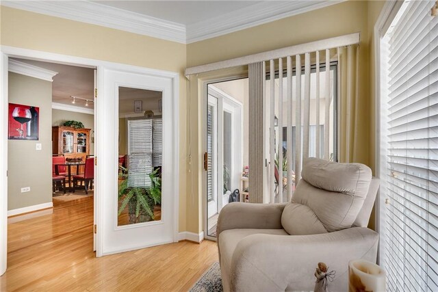 sitting room featuring crown molding, light wood-style floors, and baseboards