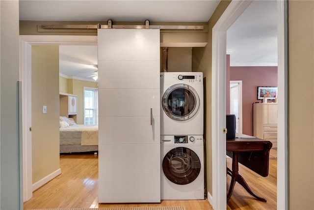 washroom featuring ornamental molding, stacked washer and clothes dryer, wood finished floors, and laundry area