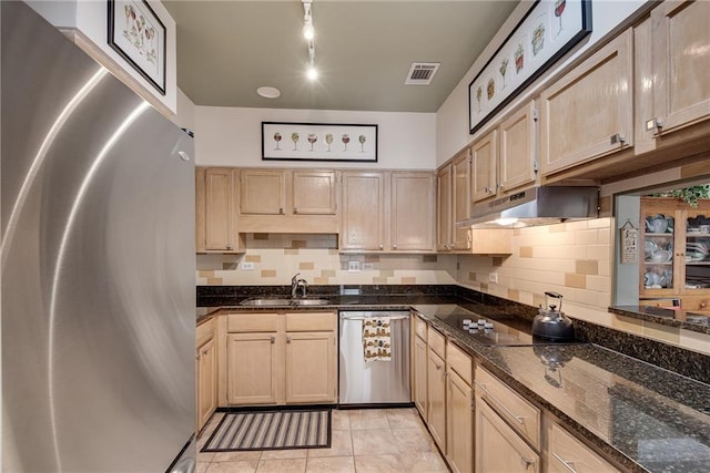 kitchen featuring visible vents, under cabinet range hood, tasteful backsplash, a sink, and stainless steel appliances
