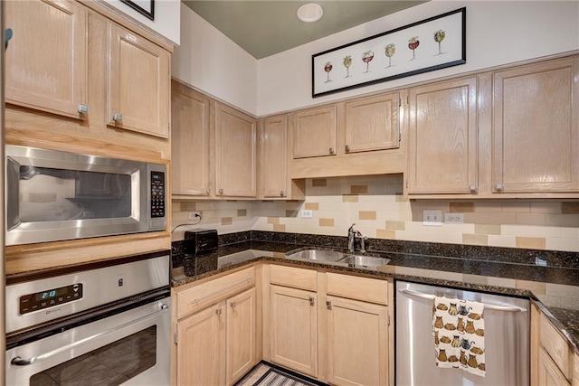 kitchen with a sink, appliances with stainless steel finishes, light brown cabinets, and tasteful backsplash
