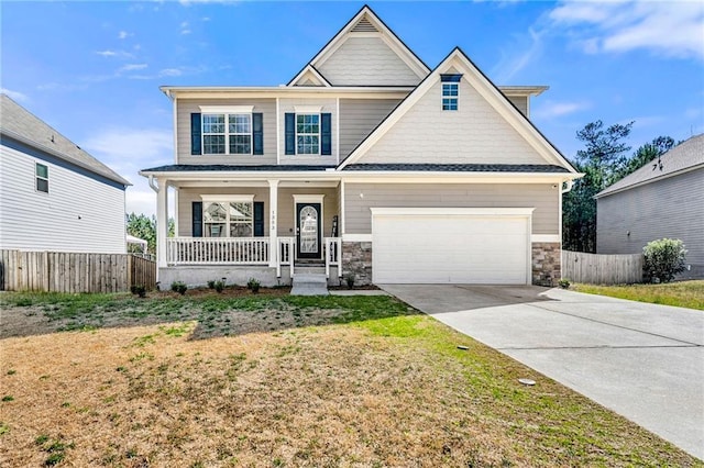 craftsman-style house featuring a porch, concrete driveway, fence, and stone siding