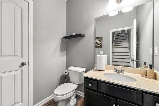 half bath with vanity, toilet, and baseboards