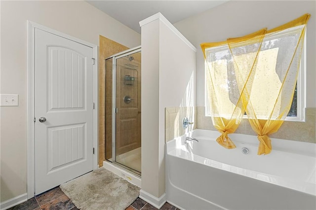 bathroom featuring a shower stall, a bath, and baseboards