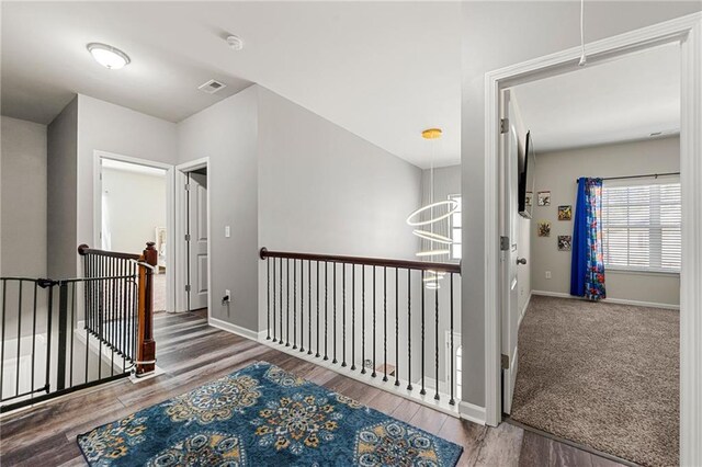 hallway featuring visible vents, wood finished floors, an upstairs landing, and baseboards