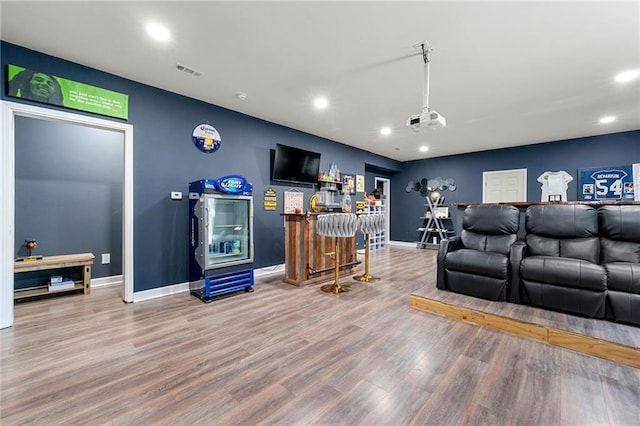 living area with recessed lighting, wood finished floors, visible vents, baseboards, and a dry bar