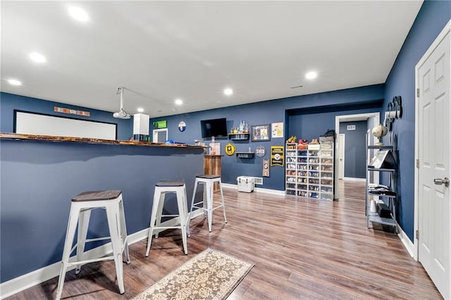 kitchen featuring baseboards, a kitchen breakfast bar, wood finished floors, and recessed lighting