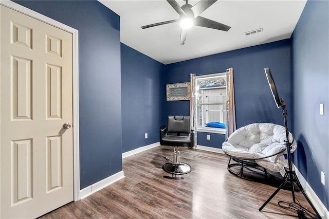 sitting room featuring ceiling fan, wood finished floors, visible vents, and baseboards