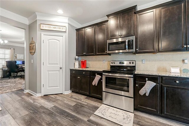 kitchen with appliances with stainless steel finishes, light wood-type flooring, crown molding, and tasteful backsplash