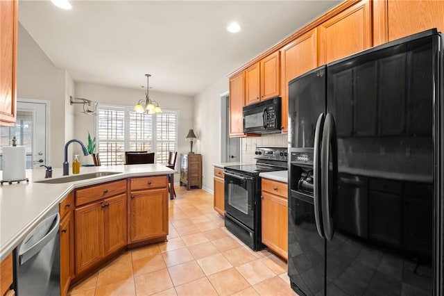 kitchen with a notable chandelier, black appliances, a sink, a peninsula, and light countertops