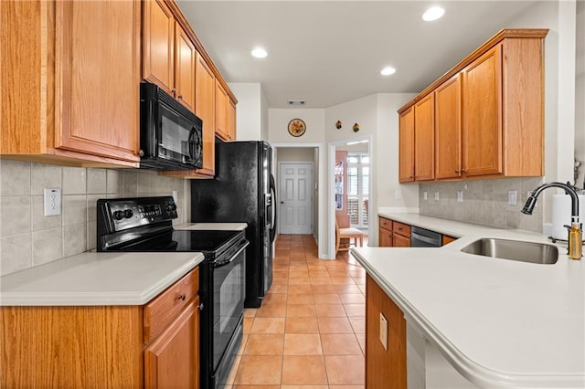 kitchen with a sink, black appliances, light tile patterned flooring, and light countertops